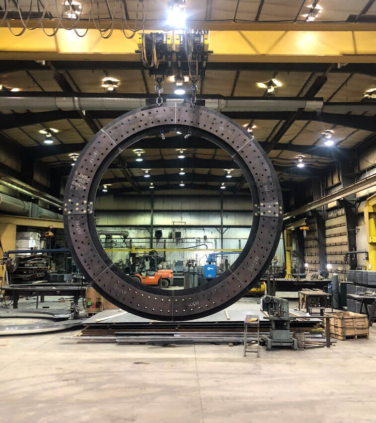 Large industrial embed ring for a wind turbine hanging from the overhead hoist inside Millwood Metalworks in Freeport, MN