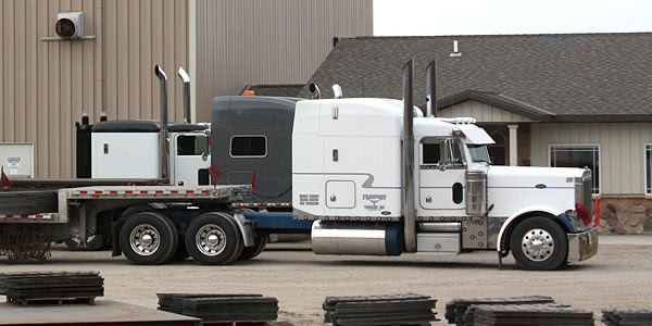 Semi tractors and flatbed trailers waiting to be loaded outside Millwood Metalworks in Freeport, MN