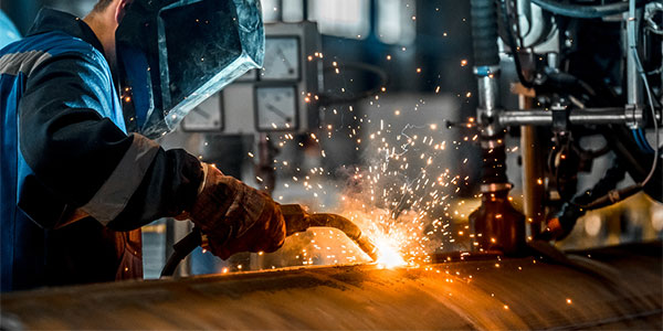 Certified welder using a welding torch to fabricate metal structures