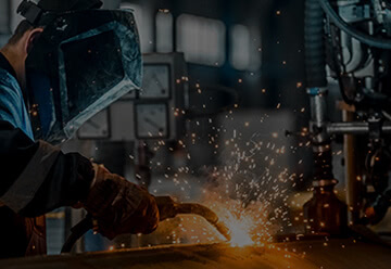Fabricator welding a piece of metal and sparks flying